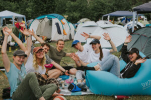Winkende Menschen in einem Zeltcamp